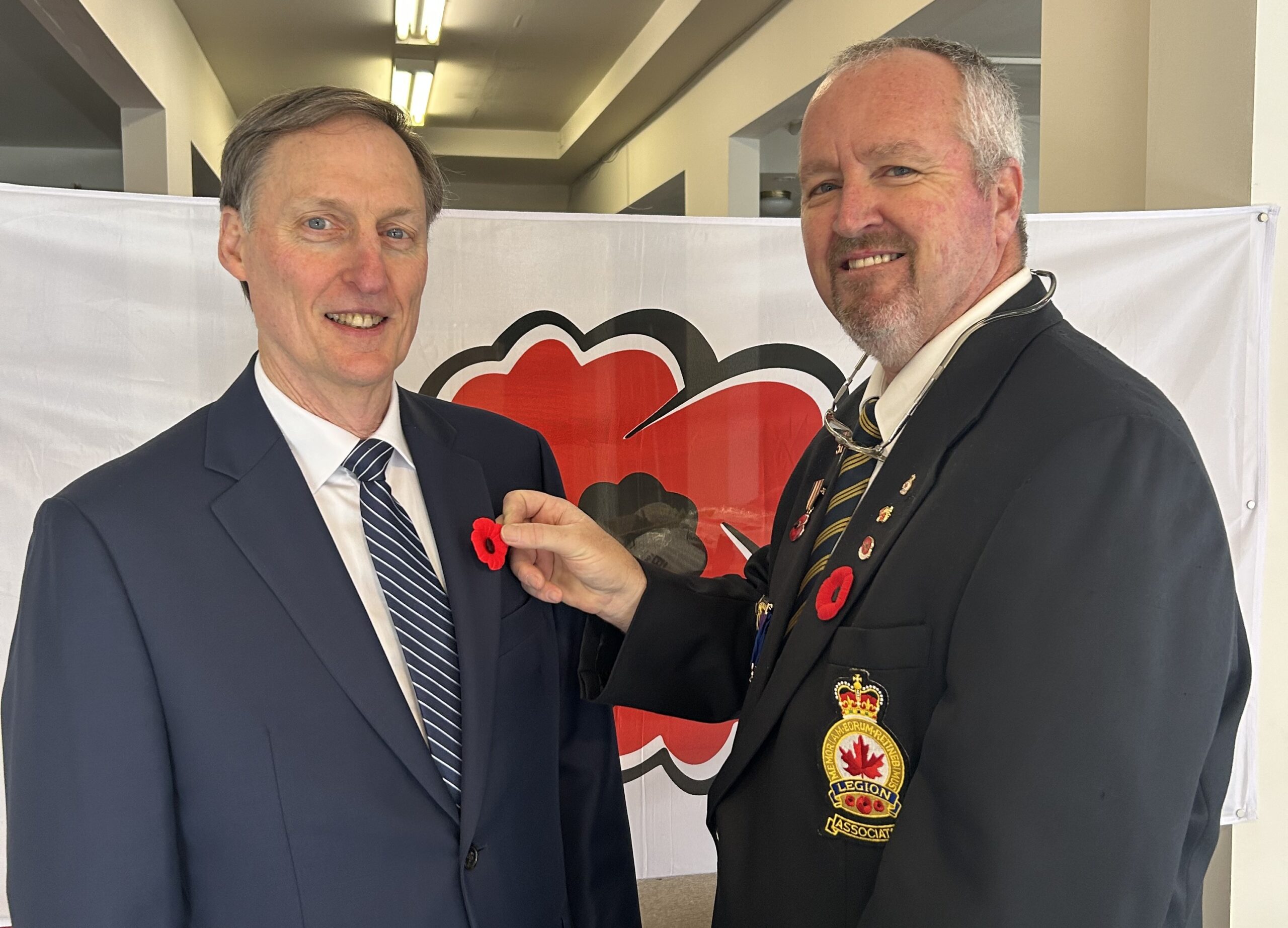 Mayor McNeil-Smith has a poppy pinned on him by a Legion member at the Poppy Office.