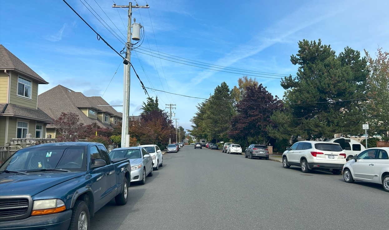 Street with cars parked and one car on road