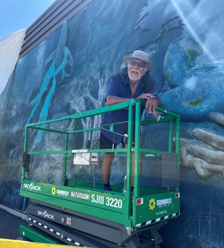 Artist, IceBear on lift in front of mural