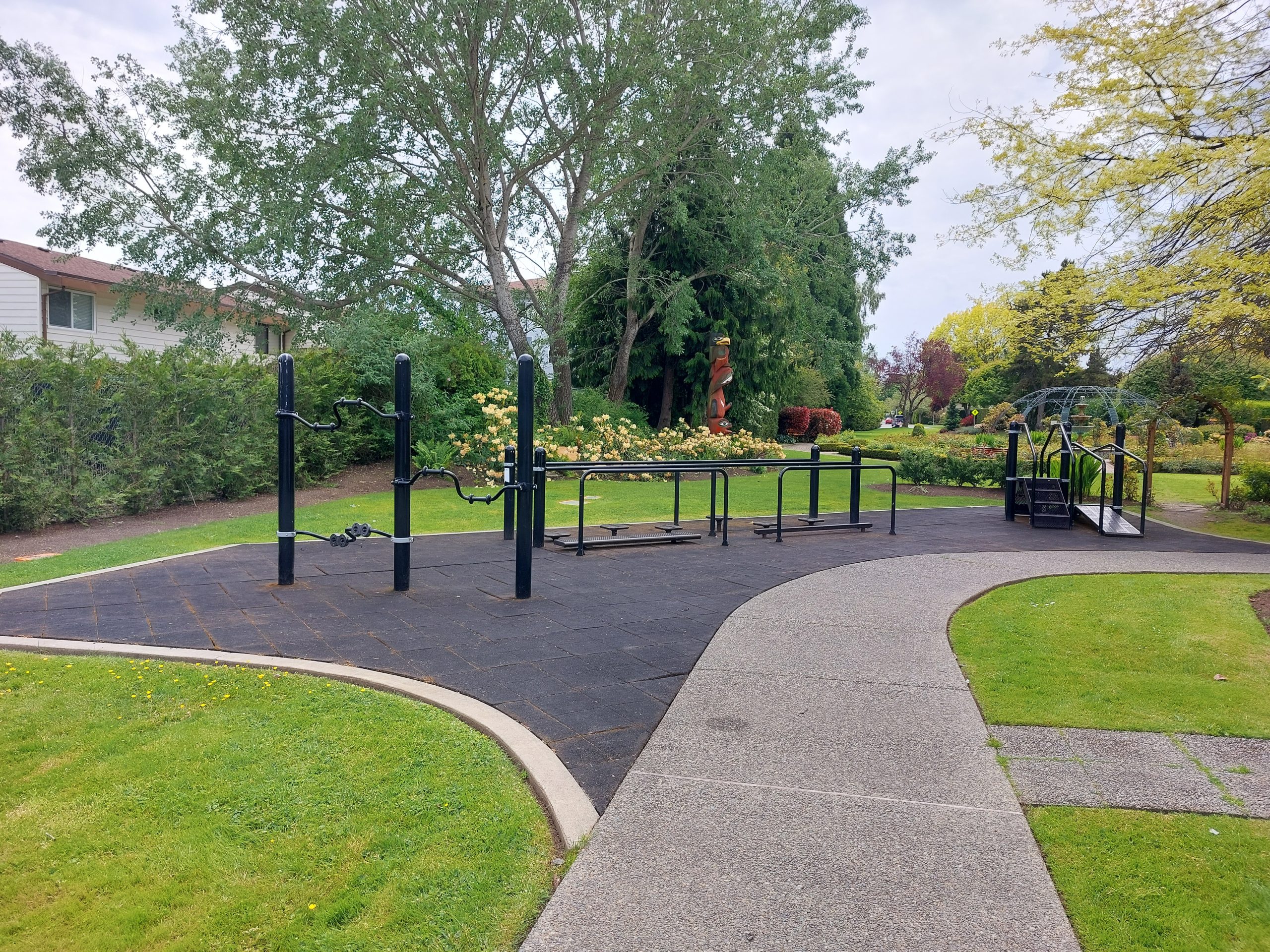 Image of exercise equipment in the Community Wellness Park with the Rose Garden in the background