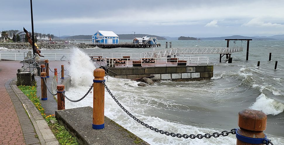 Image of a wave crashing over the waterfront walkway between the pier and Glass Beach